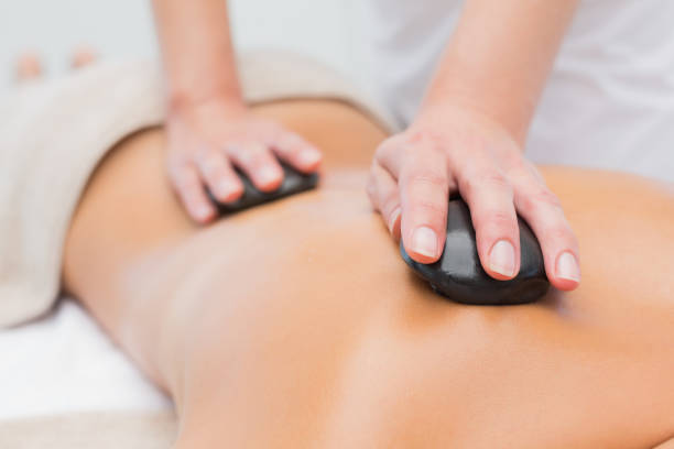 Beautiful woman receiving stone massage at spa center stock photo