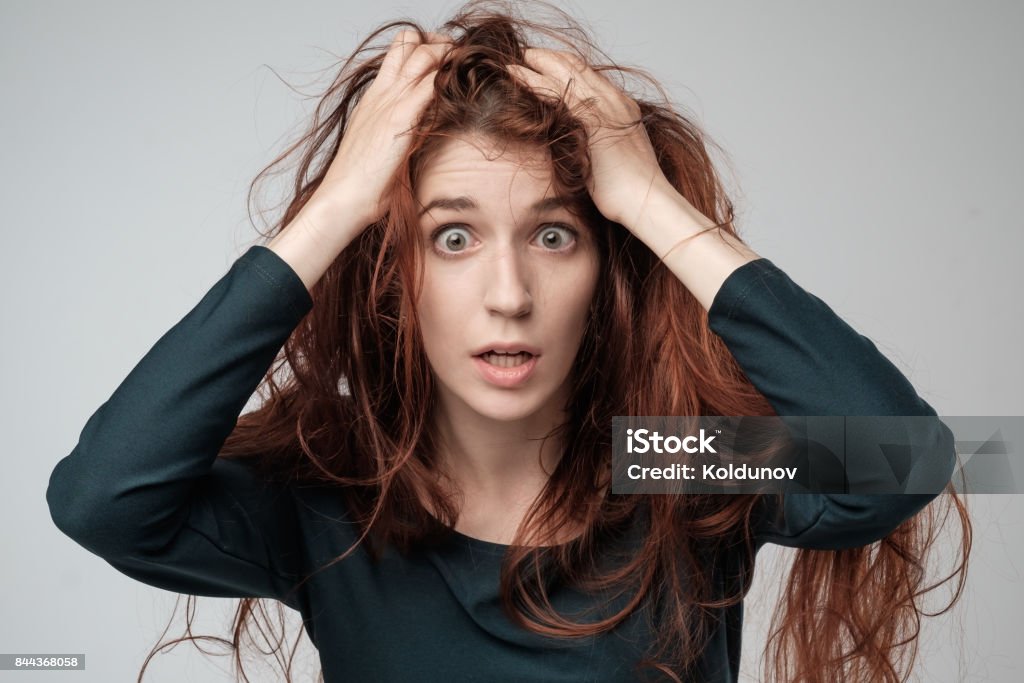 Pretty caucasian woman trying to comb hair. Shocked emotion on face Pretty caucasian woman trying to comb hair. The problem with the tangled and long hair. Shocked emotion on face Adult Stock Photo