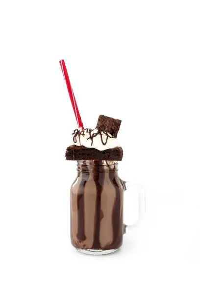 Homemade Chocolate Freakshake, Milkshake, with brownies, chocolate sauce and whipping cream on white background with copy space.