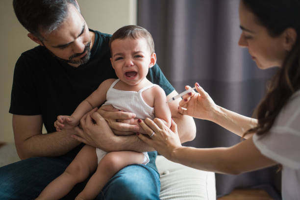 Latin parents holding crying baby and injecting her