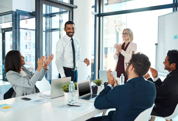 He's proven himself yet again to the team Shot of businesspeople applauding a colleague in an office clapping photos stock pictures, royalty-free photos & images