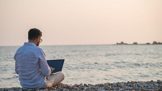 Man sitting on the beach and using laptop