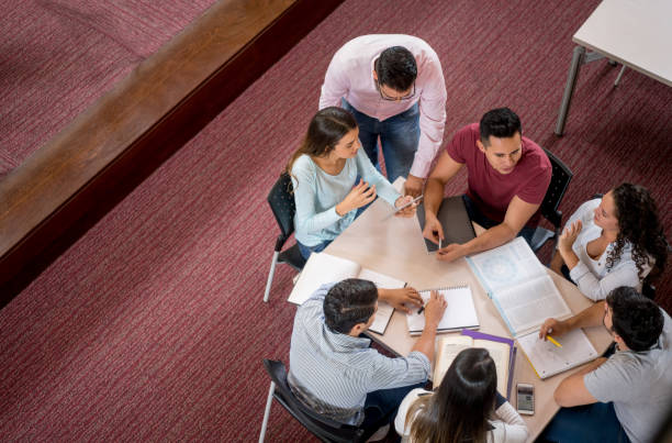 istock Teacher helping college students studying at the library 844393176