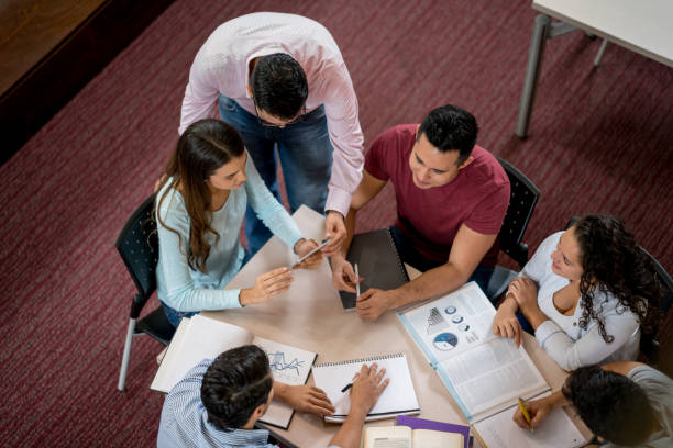 istock Librarian helping a group of students studying at the library 844393208