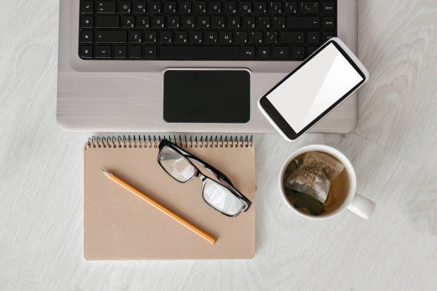 istock Concept workplace top view. Designer desk with laptop,blank screen, notebook, phone and cup tea 844393808