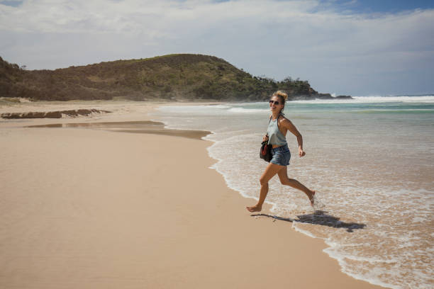 Young woman running along Sunrise Beach in Noosa Heads, Queensland, Australia.