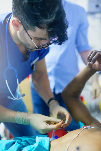 Focus is a critical skill required in trauma Shot of a doctor inserting a tube into a patient’s chest in an emergency room CHEST DRAIN stock pictures, royalty-free photos & images