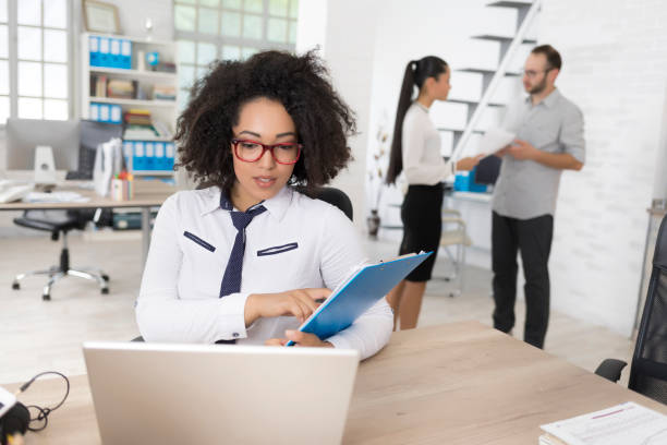 istock African businesswoman looking at documents and using laptop 844401144