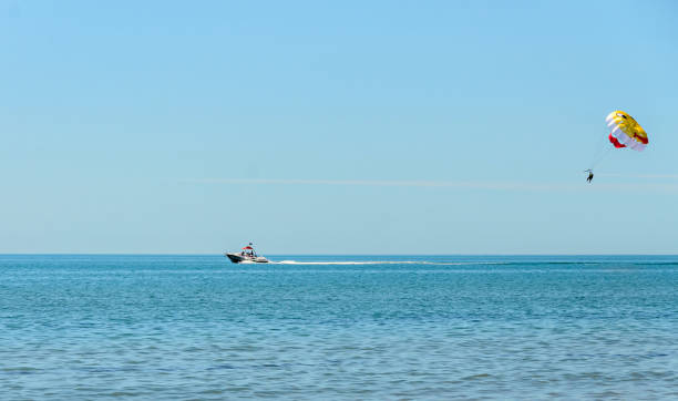 istock Colored parasail wing pulled by a boat in the sea water, Parasailing also known as parascending or parakiting 844410480