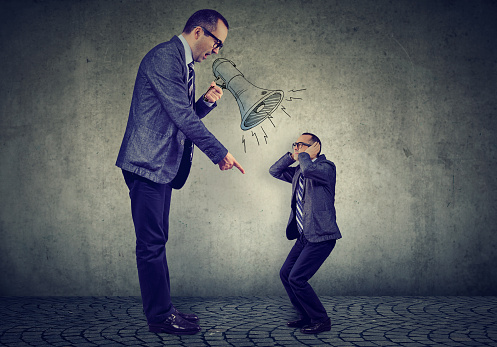 Angry business man boss screaming at himself small in megaphone