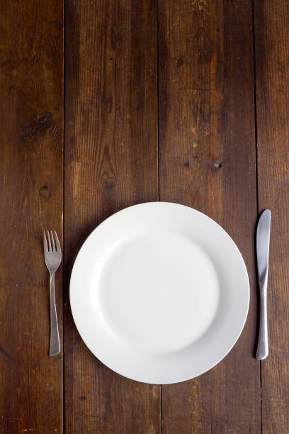 istock White plate and cutlery on wooden background 844433964