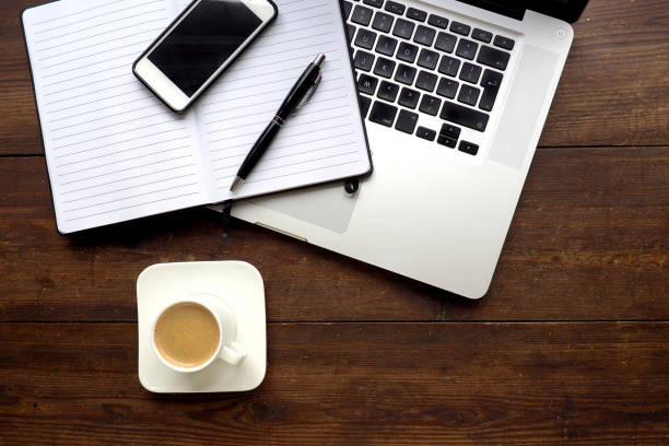 istock Laptop and notepad on wooden desk, from above 844436468