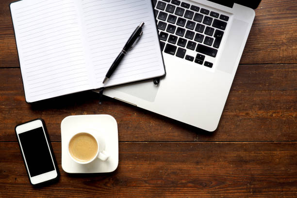 istock Laptop and notepad on wooden desk, from above 844436470