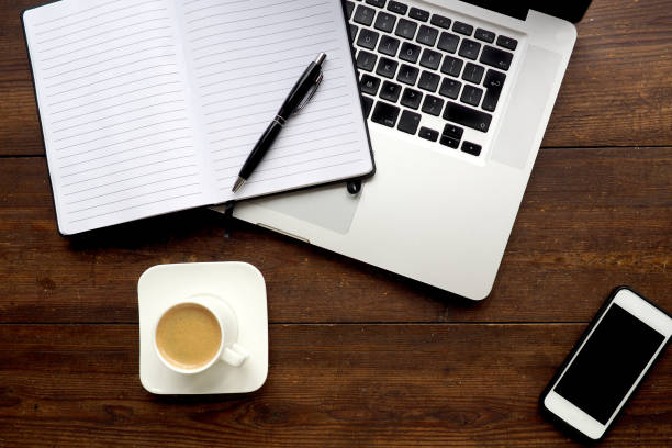 istock Laptop and notepad on wooden desk, from above 844436578