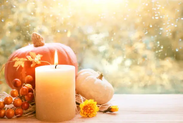 Photo of Burning candle, pumpkin and Fall decorations on a windowboard, space