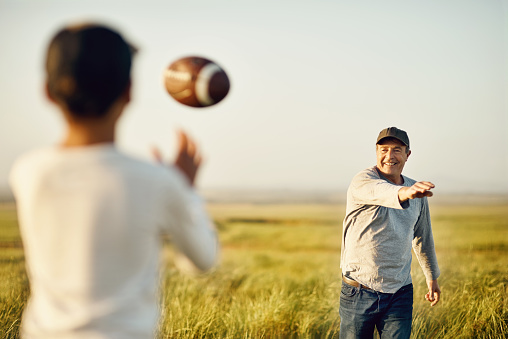 Shot of father and son playing football on an open field