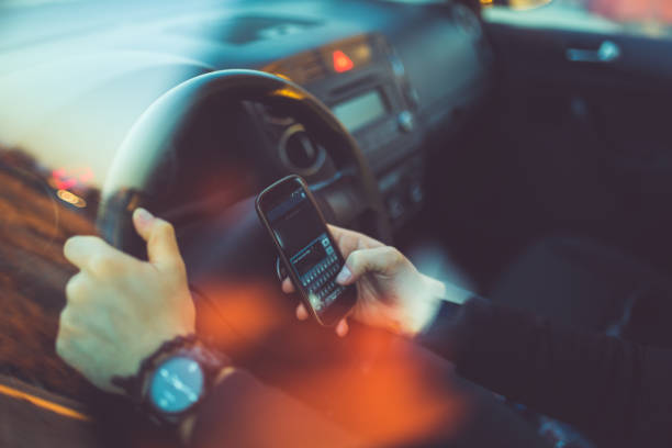 giovane uomo d'affari alla guida di un'auto e con lo smartphone - driving text messaging accident danger foto e immagini stock