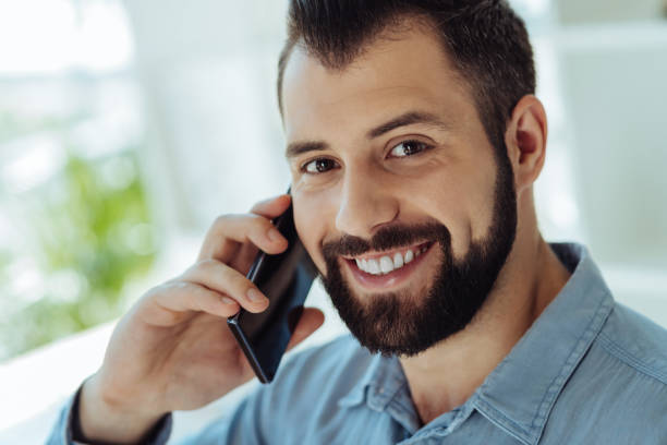 istock Bearded man talking on phone and smiling at camera 844451988