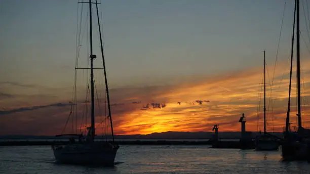 A sailingboat comes into harbor by sunrise near mallorca