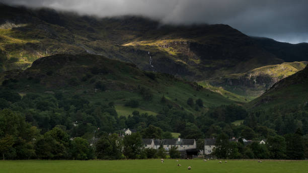 istock Consiton Village with sunlight breaking through Storm clouds onto Coniston Old Man and sheep grazing. 844459902
