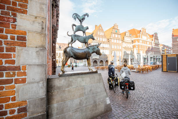 Bremen Musicians statue BREMEN, GERMANY - August 10, 2017: Couple of tourist on the bicycles near bronze statue by Gerhard Marcks depicting the Bremen Town Musicians in Bremen city, Germany brothers grimm stock pictures, royalty-free photos & images