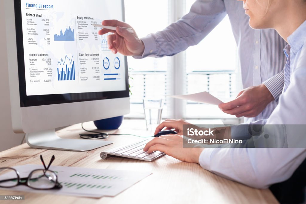 Consulting auditors auditing financial report on computer screen, business charts Team of consulting auditors auditing the financial report data of the company (balance sheet, income statement) on computer screen with business charts, fintech Cash Flow Stock Photo