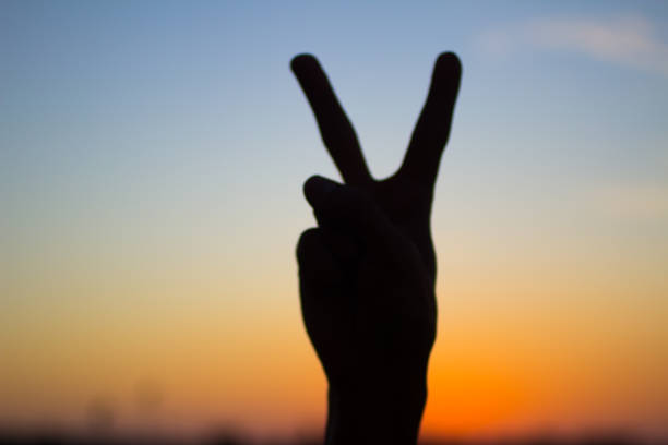istock hand silhouette showing victory sign on sunset background 844472074