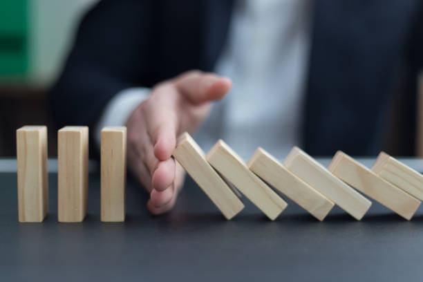 istock BUSINESSMAN HAND STOPPING DOMINO EFFECT CONCEPT 844481684