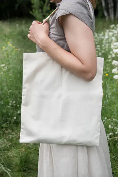 Woman holding empty linen bag outdoor. Template mock up
