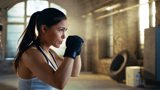 Beautiful Athletic Woman holds her Arms Ready for Defending Herself. It is a Part of Her Intensive Cross Fitness Gym Training.