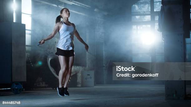 Athletic Beautiful Woman Exercises With Jump Skipping Rope In A Gym Shes Covered In Sweat From Her Intense Cross Fitness Training Dark Atmosphere Stock Photo - Download Image Now