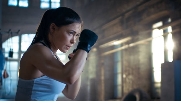 athletic woman è pronta per punch punching bag. è una donna forte e meravigliosa. si allenano in palestra. - boxing winning success challenge foto e immagini stock