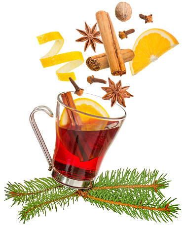 spices falling into a glass of mulled wine on a tree sprig isolated on white