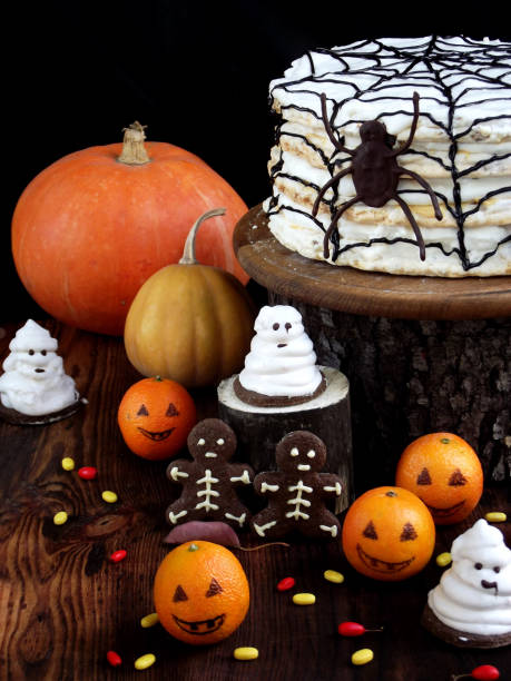 istock Funny delicious composition for Halloween with cake, biscuits, marshmallow and mandarins on the table. Sweets in the form of ghosts, skeletons, spiders and pumpkin jack 844493256