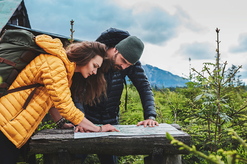 Young couple in the woods planning trip. Using map