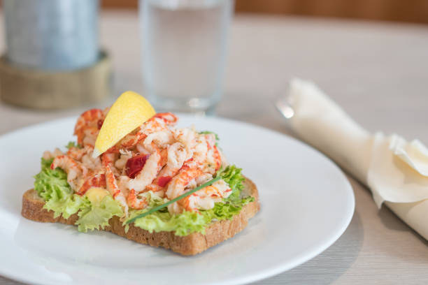 Sandwich with shrimp and lemon on plate.