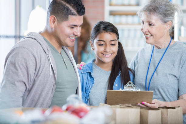 senior female food bank manager talks with volunteers - to do list organization life family imagens e fotografias de stock