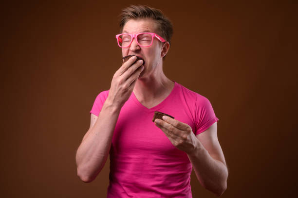 Studio shot of young handsome man with chocolate cake against colored background horizontal shot