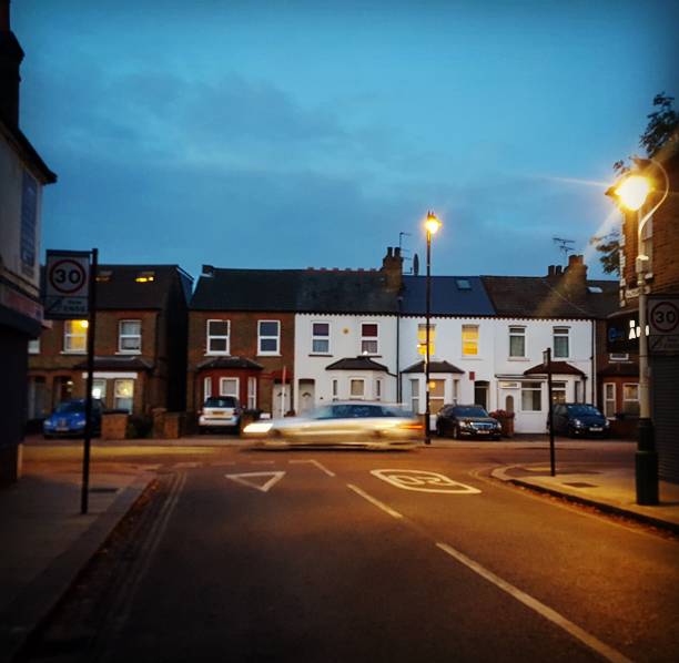 Street in Ealing, West London at dusk Motion blur as a car passes a road in Ealing, London. eanling stock pictures, royalty-free photos & images