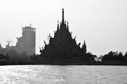 Sanctuary of Truth shadow along naklua beach, an all-wood temple construction filled with sculptures based on traditional Buddhist and Hindu motifs, contrasting with the high rise buildings in the background
