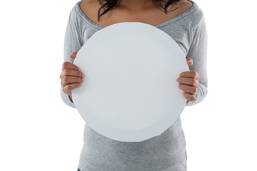 Mid section of woman holding circle shaped placard against white background