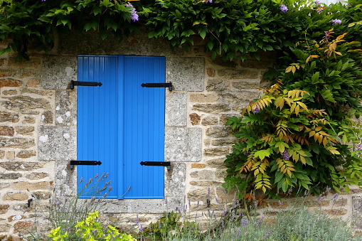 Closed blue shutters in an ancient building in rural Brittany, France