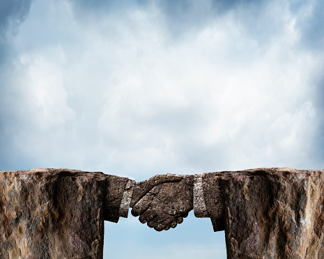 Two rocky cliffs are joined by a stone handshake against a cloudy background.