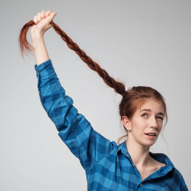 istock Funny red haired model girl with long braid hair. She holds long braid up. 844569686