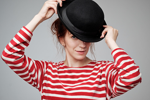 Close up portrait of a smiling young womanwith red hair playing with hat anf flirting
