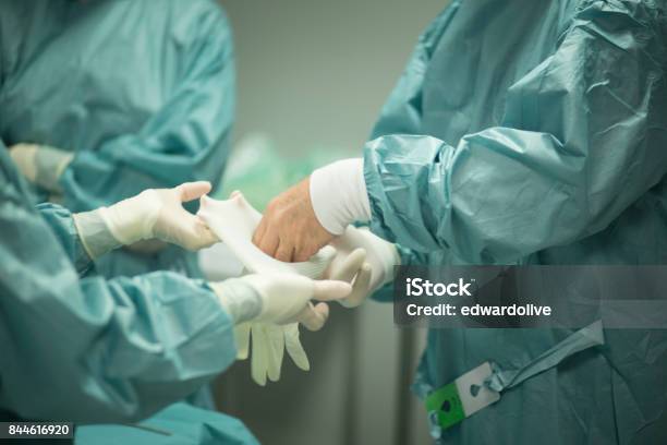 Chirurg In Der Krankenhauschirurgie In Sterilen Uniformpeelings In Der Notaufnahme Des Operationssaals Bei Chirurgischen Operationen Stockfoto und mehr Bilder von Schutzhandschuh