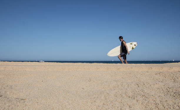 istock Surfer with surfboard walking on the beach 844627580