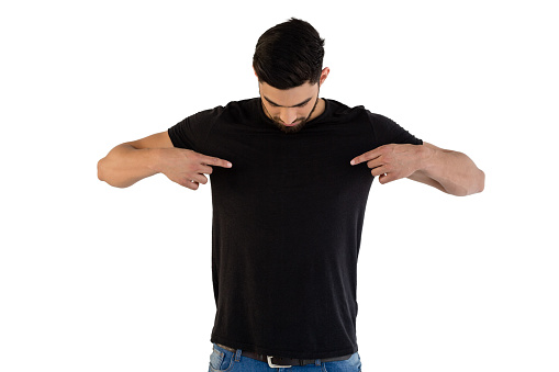 Handsome man pointing at t-shirt against white background
