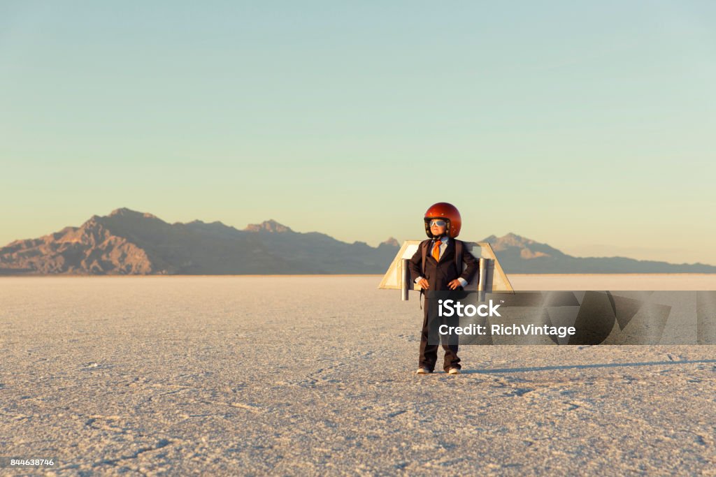 Young Businessman Wearing Jet Pack A young business boy and entrepreneur is dressed in a business suit and helmet wearing a jet pack on the Bonneville Salt Flats in Utah, USA. He is ready to try out the new business ideas and take his new business to new heights. Jet Pack Stock Photo