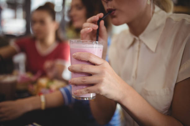 istock Midsection of woman drinking milkshake at cafe 844648452